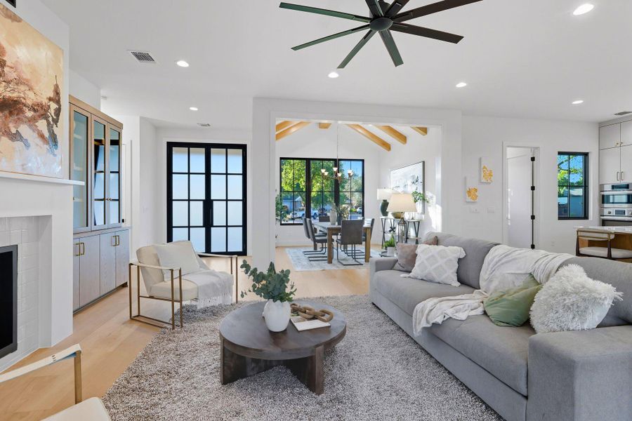 Living room featuring a fireplace, recessed lighting, light wood-style flooring, a ceiling fan, and a chandelier