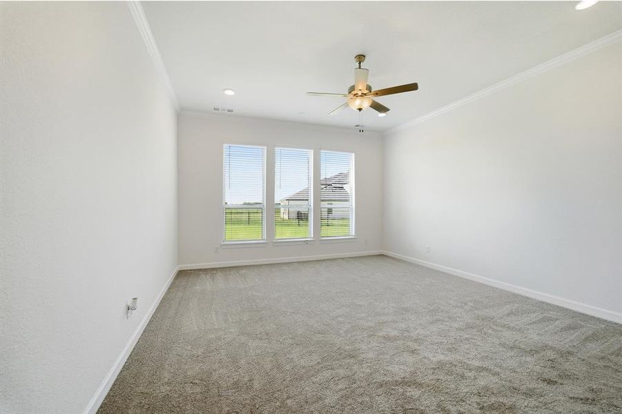 Spacious room featuring neutral carpeting, a triple window array with horizontal blinds, a ceiling fan with integrated lighting, recessed lighting, and crown molding