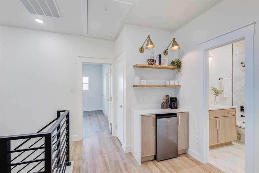 Bar featuring stainless steel fridge, light brown cabinets, and light hardwood / wood-style flooring