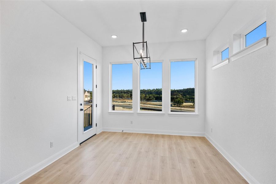 Unfurnished dining area featuring suspended lighting and light wood-style flooring