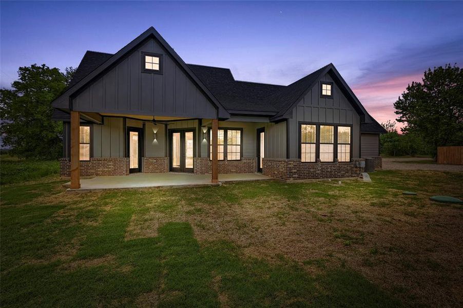 Back of house featuring board and batten siding, a yard, and french doors