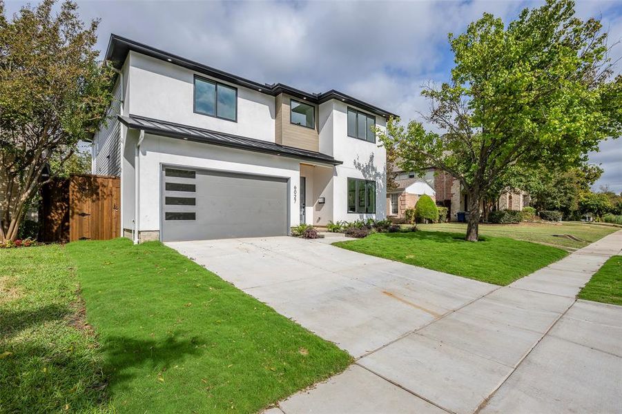 Contemporary house featuring a standing seam roof, a metal roof, a garage, concrete driveway, and stucco siding Contemporary house featuring a standing seam roof, a metal roof, a garage, concrete driveway, and stucco siding