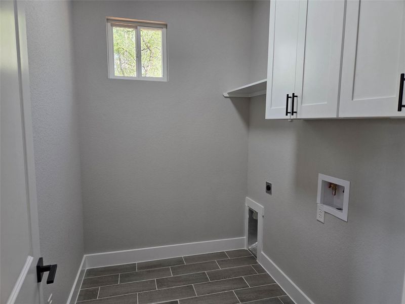 Laundry room featuring cabinet space, hookup for an electric dryer, and washer hookup Laundry room featuring cabinet space, hookup for an electric dryer, and washer hookup