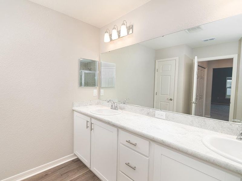 The spacious en-suite bath includes a tiled, glass-enclosed shower, a linen closet, and a closeted toilet.