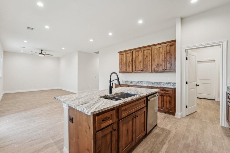 Kitchen featuring a center island with sink, dishwasher,wood plank tile floor, a ceiling fan, and a sink Kitchen featuring a center island with sink, dishwasher,wood plank tile floor, a ceiling fan, and a sink