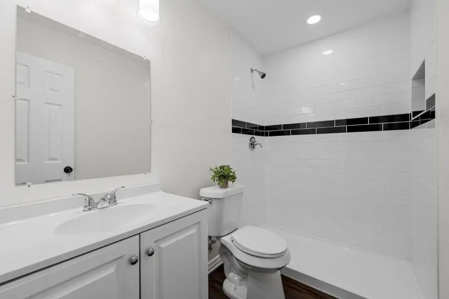 Full bathroom featuring vanity, a tile shower, recessed lighting, and wood finished floors Full bathroom featuring vanity, a tile shower, recessed lighting, and wood finished floors