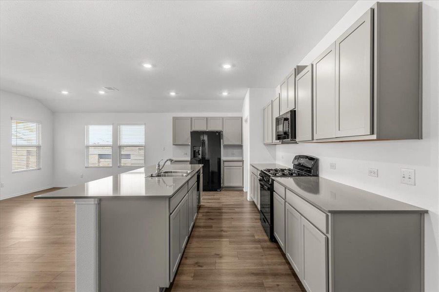 Kitchen with gray cabinetry, black appliances, dark wood-style floors, an island with sink, and recessed lighting