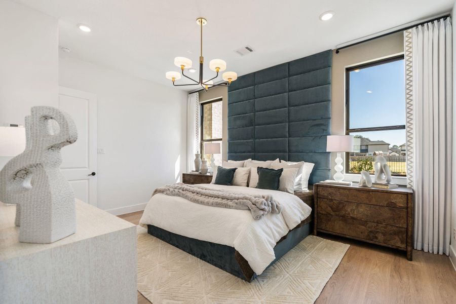 Tranquil first floor primary bedroom retreat highlighted by a dramatic upholstered accent wall