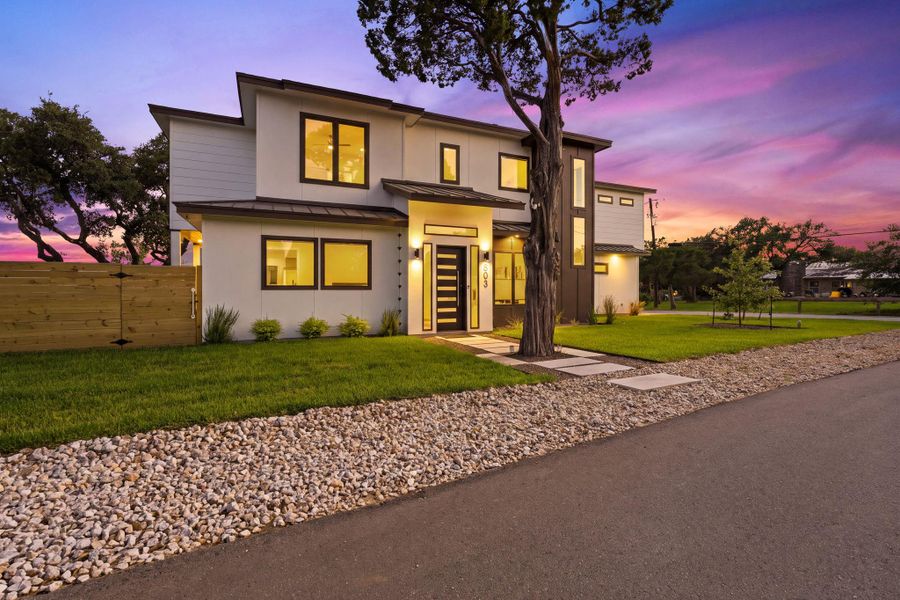 Clean architectural lines define this modern two-story home with manicured green lawns.