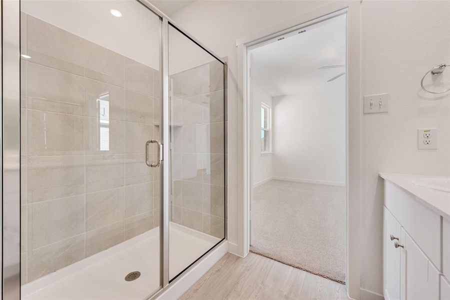 Bathroom featuring vanity, wood-type flooring, and a shower with door