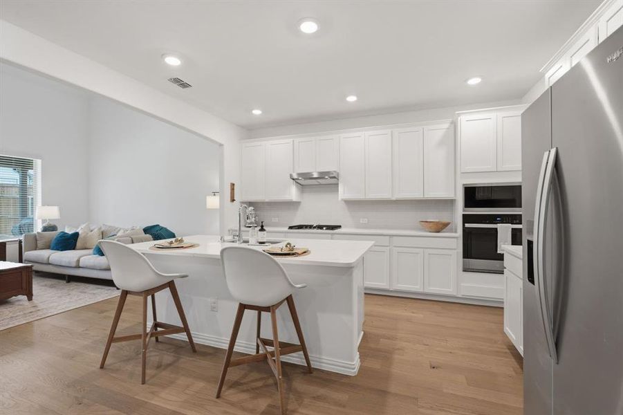 Bright white chef’s kitchen with quartz countertops, gas cooktop, stainless appliances, and a large island perfect for everyday living and entertaining.