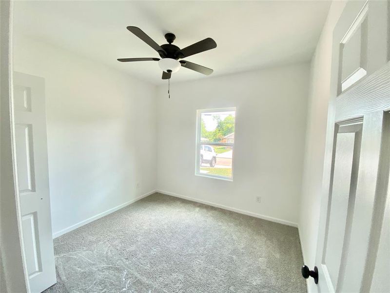 Carpeted empty room featuring ceiling fan