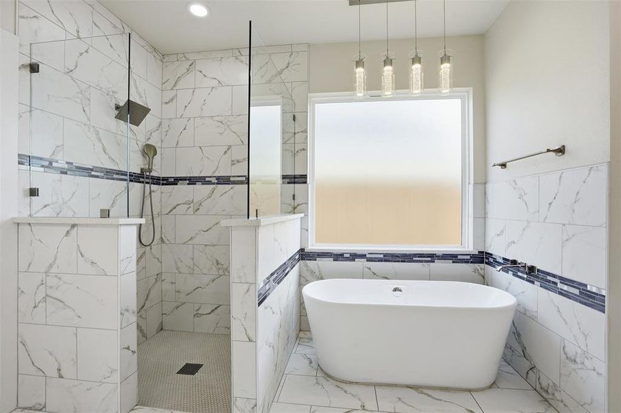 Freestanding soaking tub with a tiled surround featuring a decorative mosaic accent band