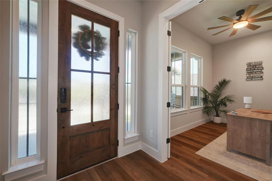 Rich wood-finish flooring enhances this entryway, featuring a solid wood front door with frosted glass panels and sidelights