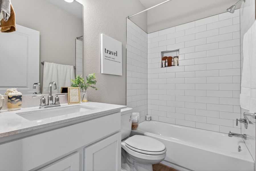 Full bathroom featuring a textured wall, shower / tub combination, and vanity