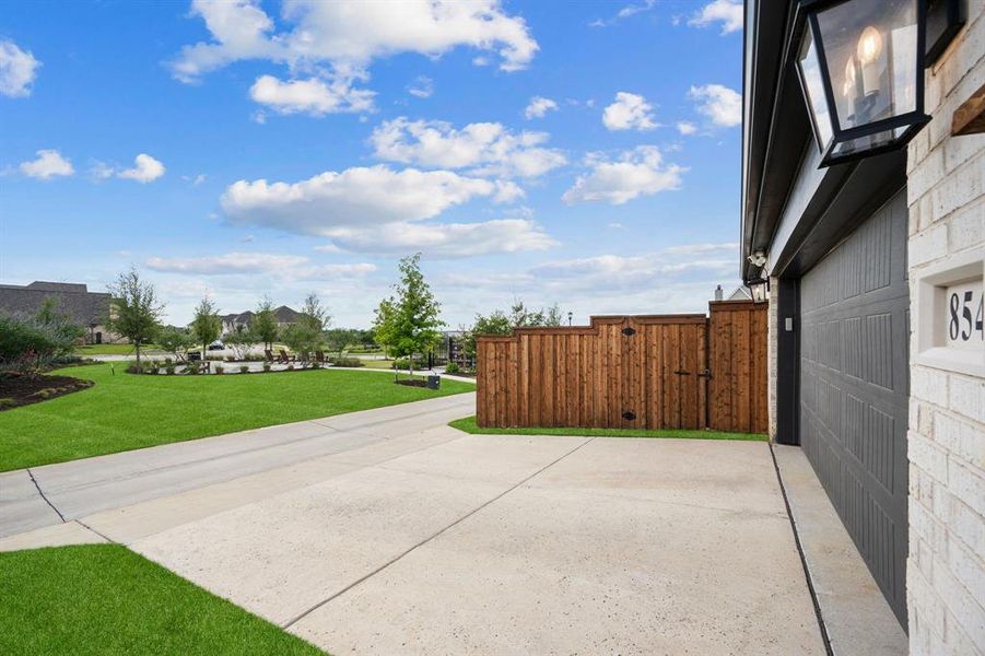 Property exterior featuring a gray garage door, white brick facade, and backing to the community pocket park with stunning views of the lake.