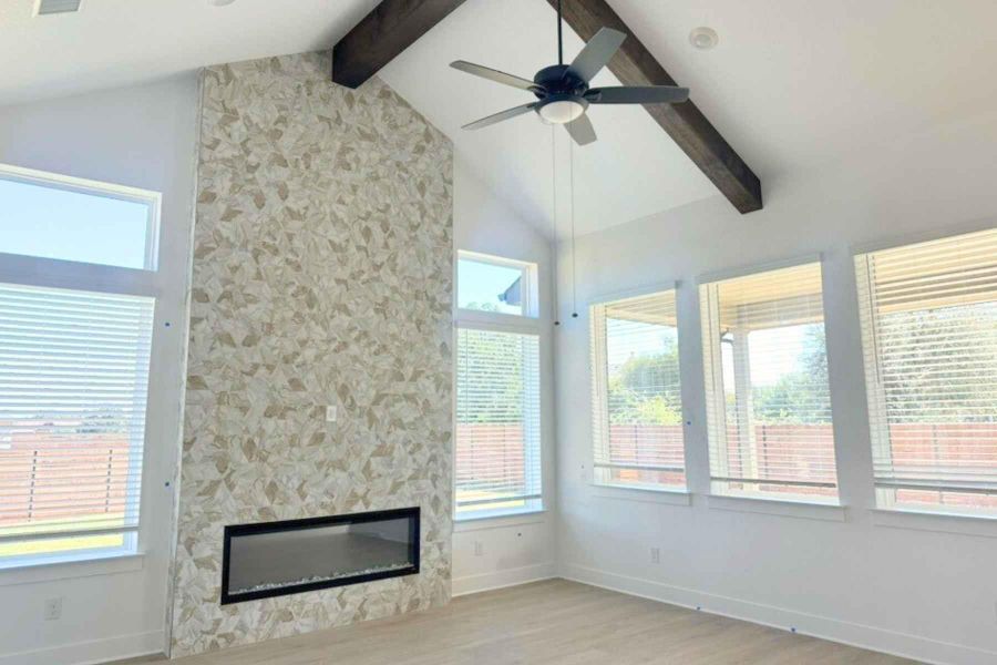 Unfurnished living room featuring light wood-style flooring, ceiling fan, a fireplace, plenty of natural light, and beam ceiling Unfurnished living room featuring light wood-style flooring, ceiling fan, a fireplace, plenty of natural light, and beam ceiling