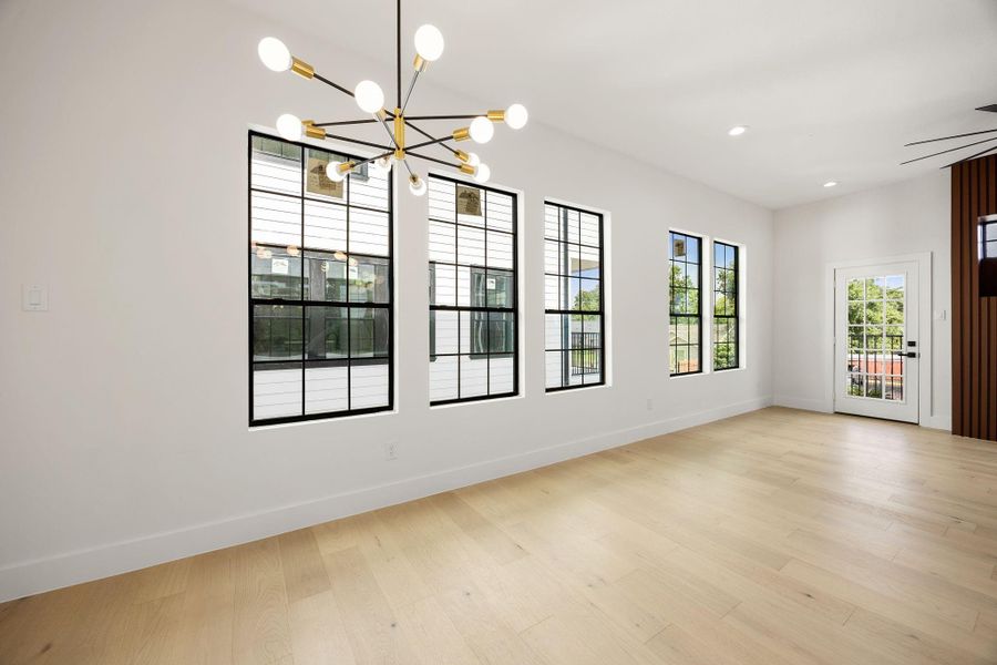 Bright dining area featuring large windows, designer lighting, and direct access to the balcny.