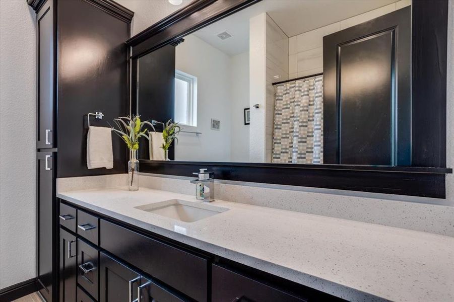 Bathroom with vanity, curtained shower, and a textured wall