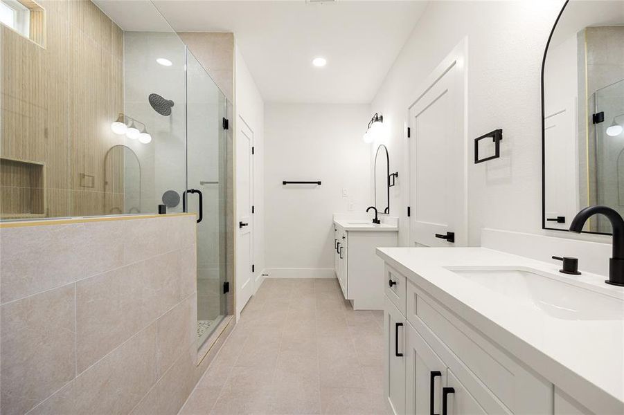 Stylish & Spacious Primary BathThis modern primary bathroom features a double vanity with quartz countertops, black fixtures, and ample storage. The frameless glass walk-in shower includes a rainfall showerhead and elegant tile accents. A perfect blend of style and comfort!