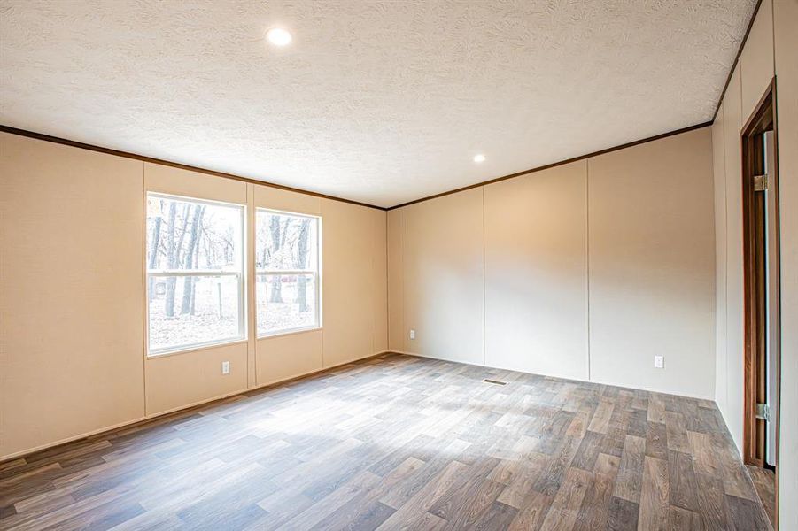 Empty room with crown molding, a textured ceiling, light wood finished floors, recessed lighting, and a decorative wall Empty room with crown molding, a textured ceiling, light wood finished floors, recessed lighting, and a decorative wall