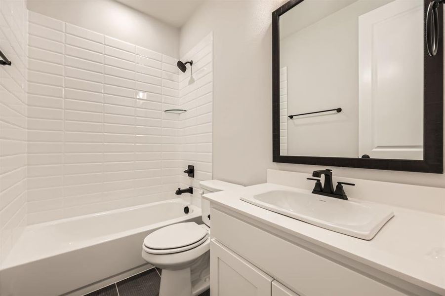 Full bathroom with toilet, tiled shower / bath combo, vanity, and tile patterned floors