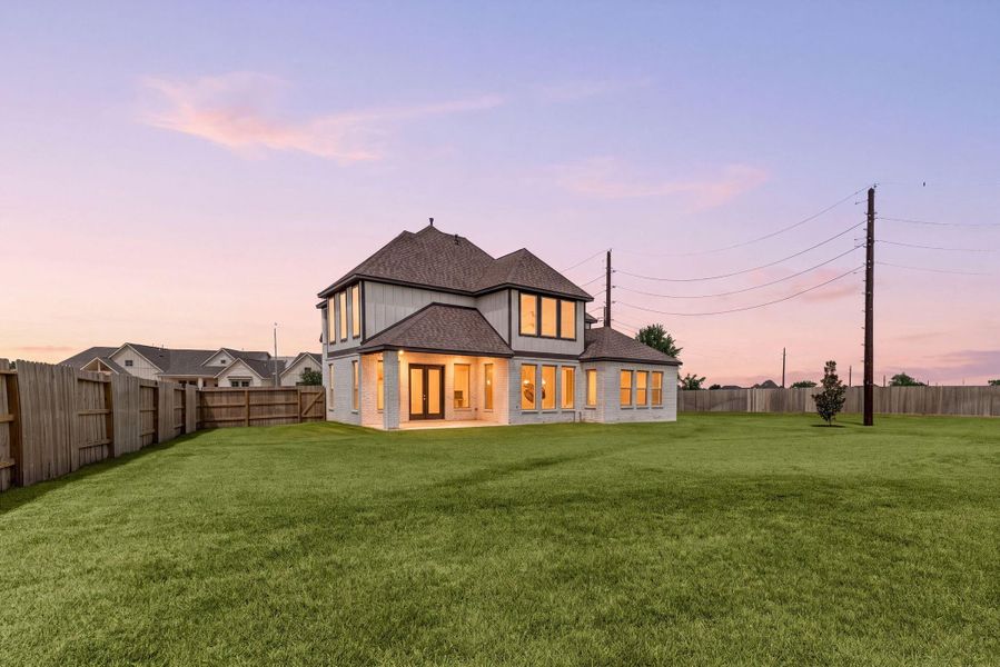 Charming two-story home with large windows, nestled on an expansive, fenced lot, perfect for privacy and outdoor activities.