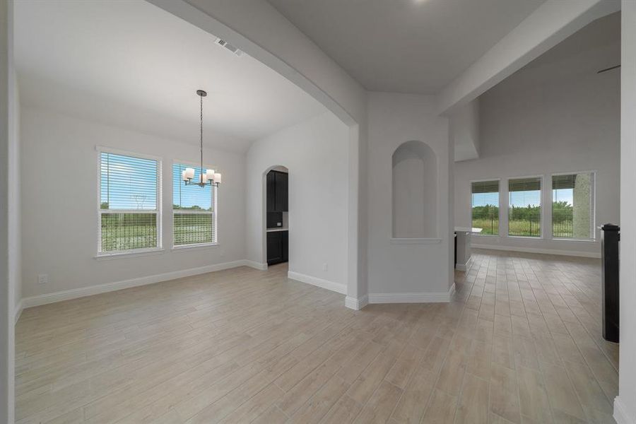 Unfurnished living room featuring light wood-type flooring, a healthy amount of sunlight, and a chandelier