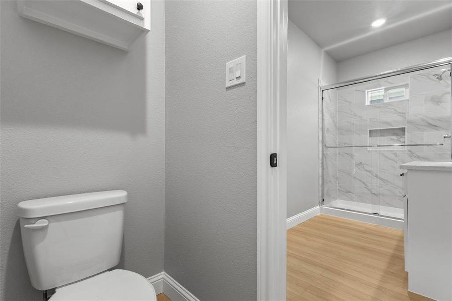 Full bathroom featuring a textured wall, a marble finish shower, and light wood-type flooring, Jack & jill