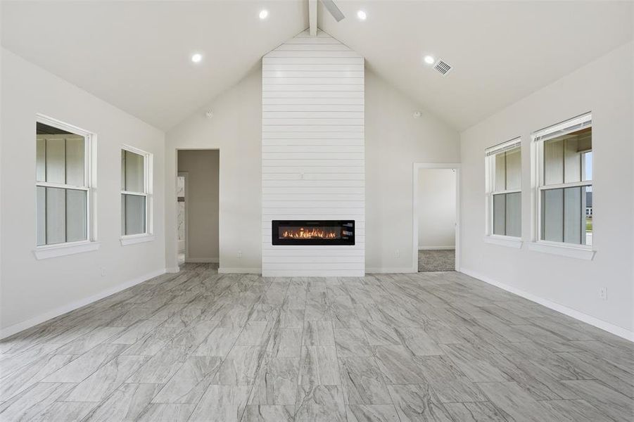 Spacious living area featuring a vaulted ceiling and a shiplap-clad fireplace with a linear insert