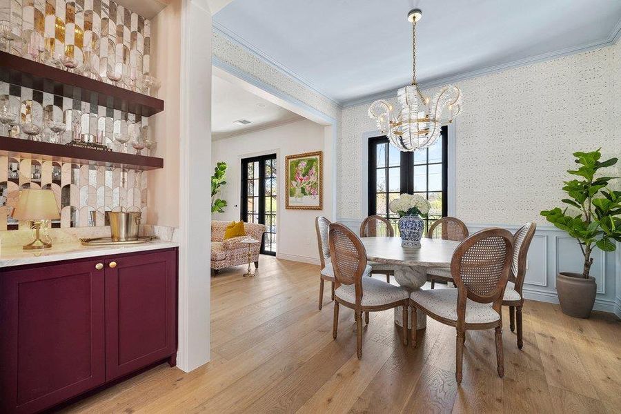 Dining area with crown molding, light wood-type flooring, and a chandelier