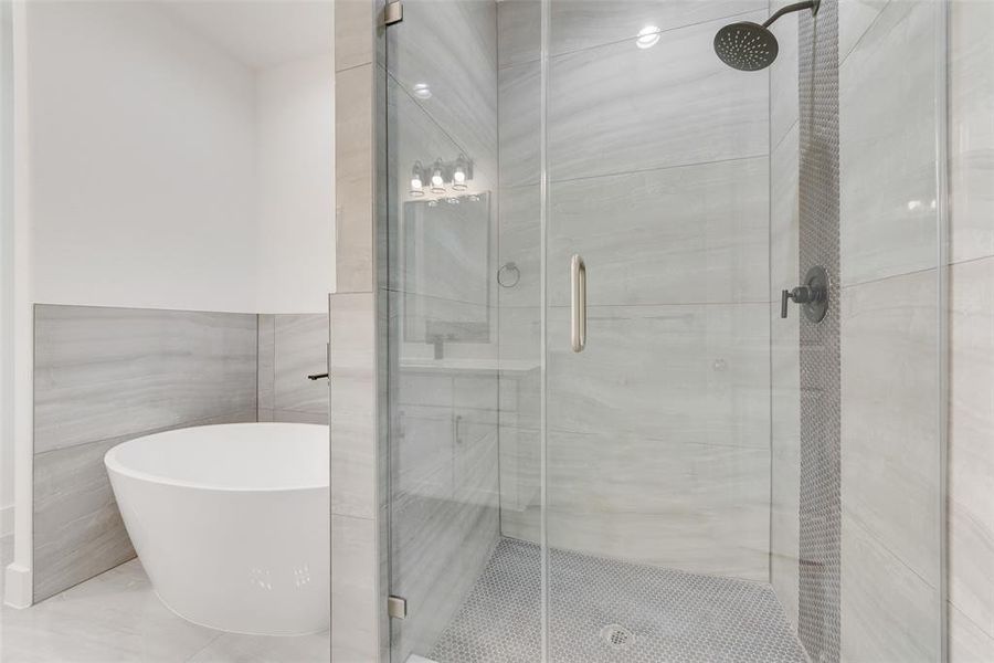 Bathroom with tile walls, a shower stall, and a freestanding tub Bathroom with tile walls, a shower stall, and a freestanding tub