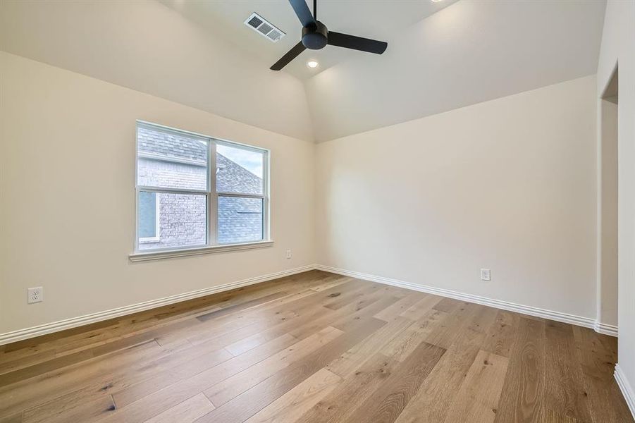 Secondary bedroom with high vaulted ceiling, ceiling fan, and light hardwood / wood-style flooring