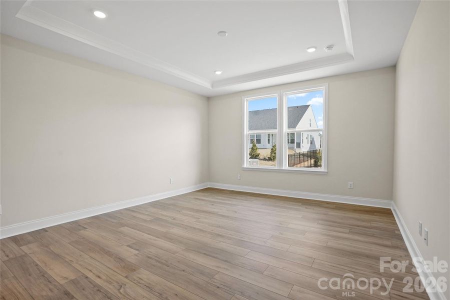 Large primary bedroom with tray ceiling and EVP flooring