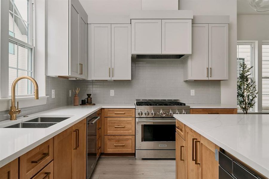 Modern kitchen featuring a dual-tone cabinetry design, white countertops, and stainless steel appliances Modern kitchen featuring a dual-tone cabinetry design, white countertops, and stainless steel appliances