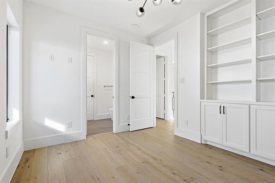 This versatile flex space features built-in floor-to-ceiling shelving and cabinetry with direct access to a full bathroom.