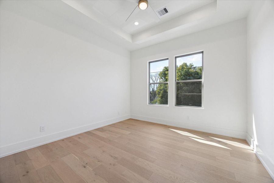 Fourth bedroom with a tray ceiling, recessed lighting, two large windows and a closet with built-ins.