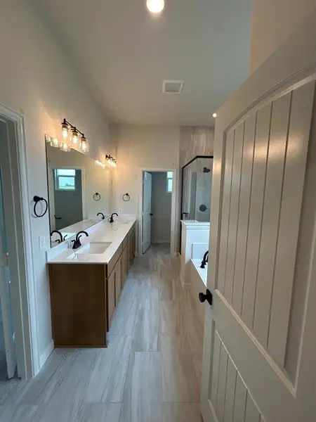 Bathroom featuring a dual vanity with light-colored countertops, matte black fixtures, and a tiled shower enclosure