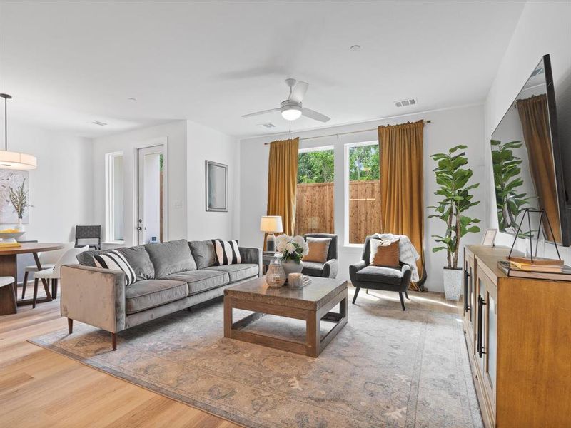 Living room featuring light wood-style floors, ceiling fan, and visible vents