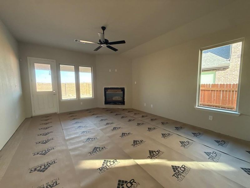 Unfurnished living room featuring a glass covered fireplace and a ceiling fan