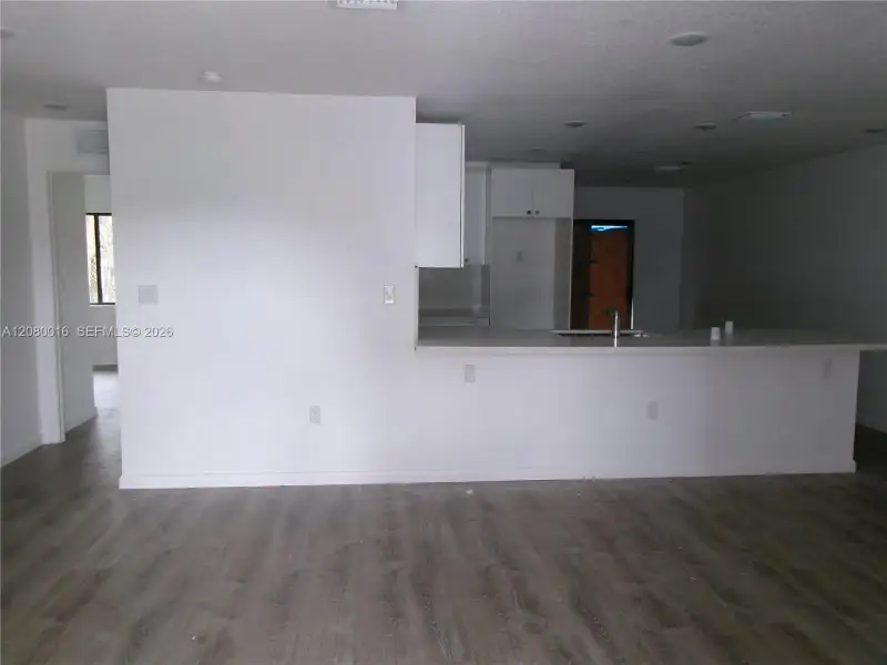 Kitchen area featuring a peninsula, recessed ceiling lighting, wood-finish flooring, and white cabinetry