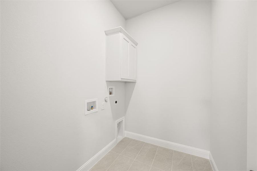 Laundry area featuring hookup for a washing machine, electric dryer hookup, cabinet space, hookup for a gas dryer, and light tile patterned flooring