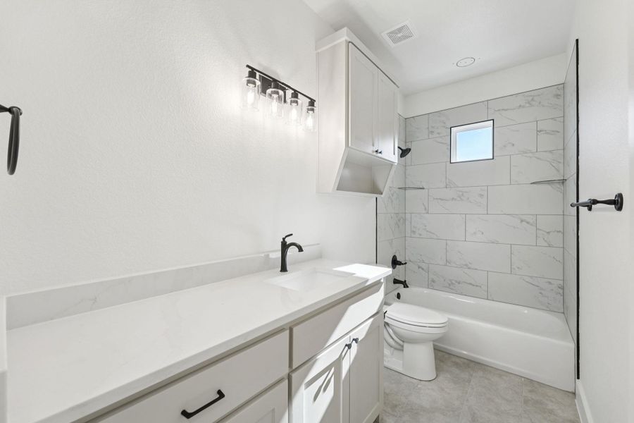 Bathroom with vanity, washtub / shower combination, and light tile patterned floors