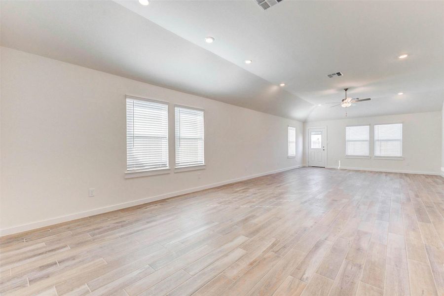 The open-concept living room offers expansive space, vaulted ceilings, and tons of natural light from multiple windows. Perfect for entertaining or relaxing, this airy retreat features recessed lighting and durable wood-look tile flooring that runs throughout the main areas. The open-concept living room offers expansive space, vaulted ceilings, and tons of natural light from multiple windows. Perfect for entertaining or relaxing, this airy retreat features recessed lighting and durable wood-look tile flooring that runs throughout the main areas.