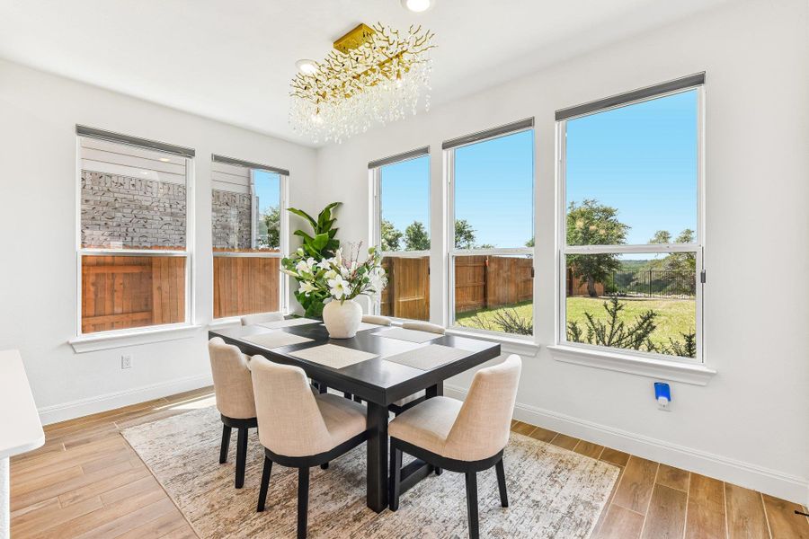 A radiant chandelier illuminates this dining space, offering serene backyard views through multiple large windows.
