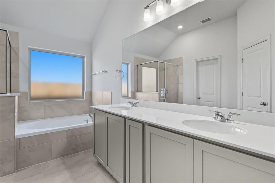 Full bath featuring a shower stall, lofted ceiling, a bath, double vanity, and light tile patterned floors Full bath featuring a shower stall, lofted ceiling, a bath, double vanity, and light tile patterned floors