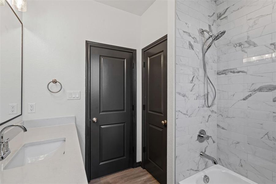 Full bath with tub / shower combination, wood finished floors, and vanity