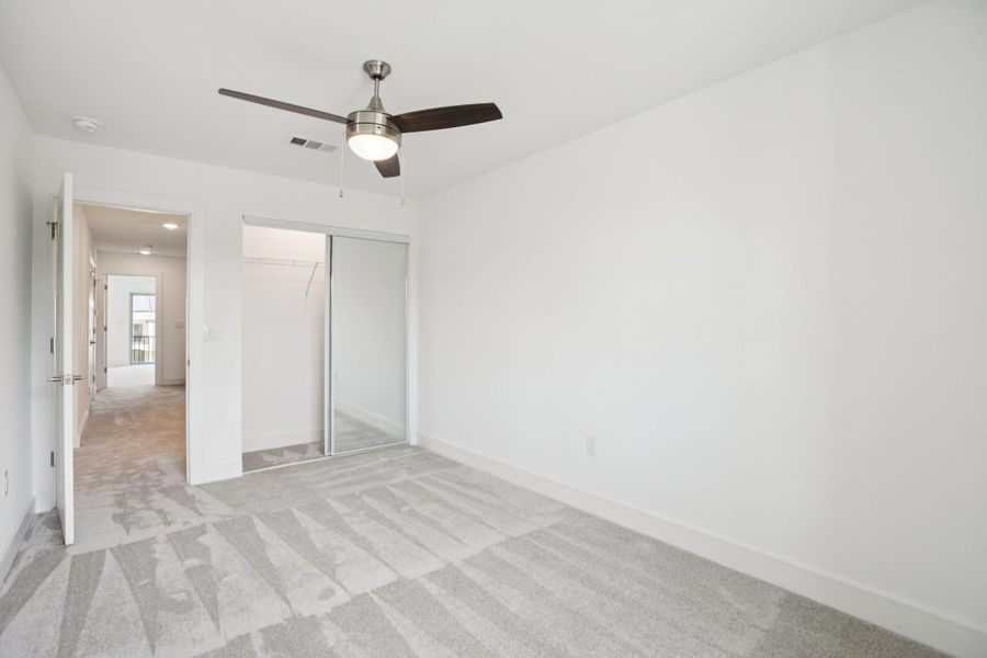 Unfurnished bedroom with light colored carpet, ceiling fan, and a closet