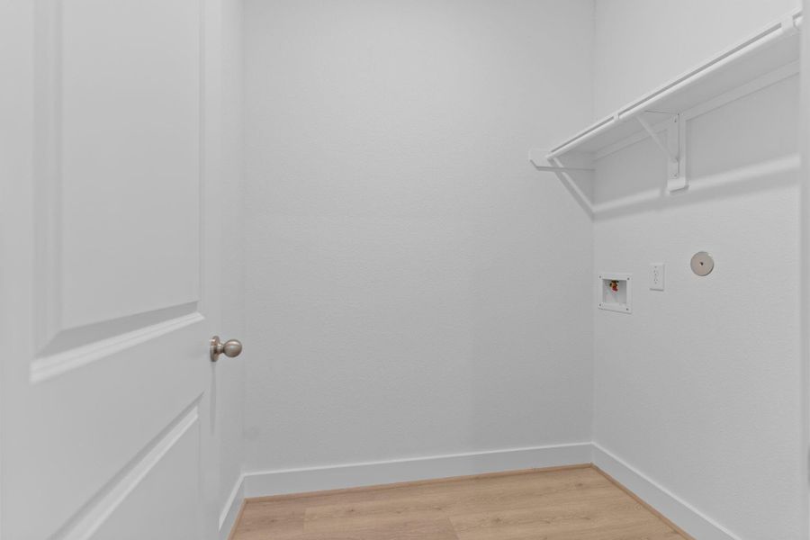 Well-appointed utility room features built-in shelving, washer and dryer connections, and woodlike vinyl plank flooring—offering both convenience and functionality for everyday laundry tasks. **Image Representative of Plan Only and May Vary as Built**.