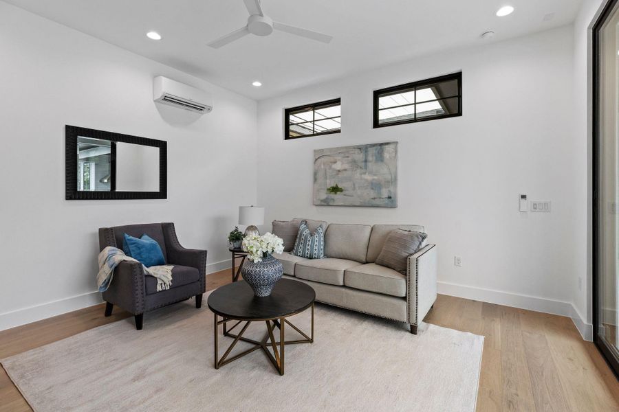 Living room featuring an AC wall unit, light wood-type flooring, recessed lighting, baseboards, and a ceiling fan